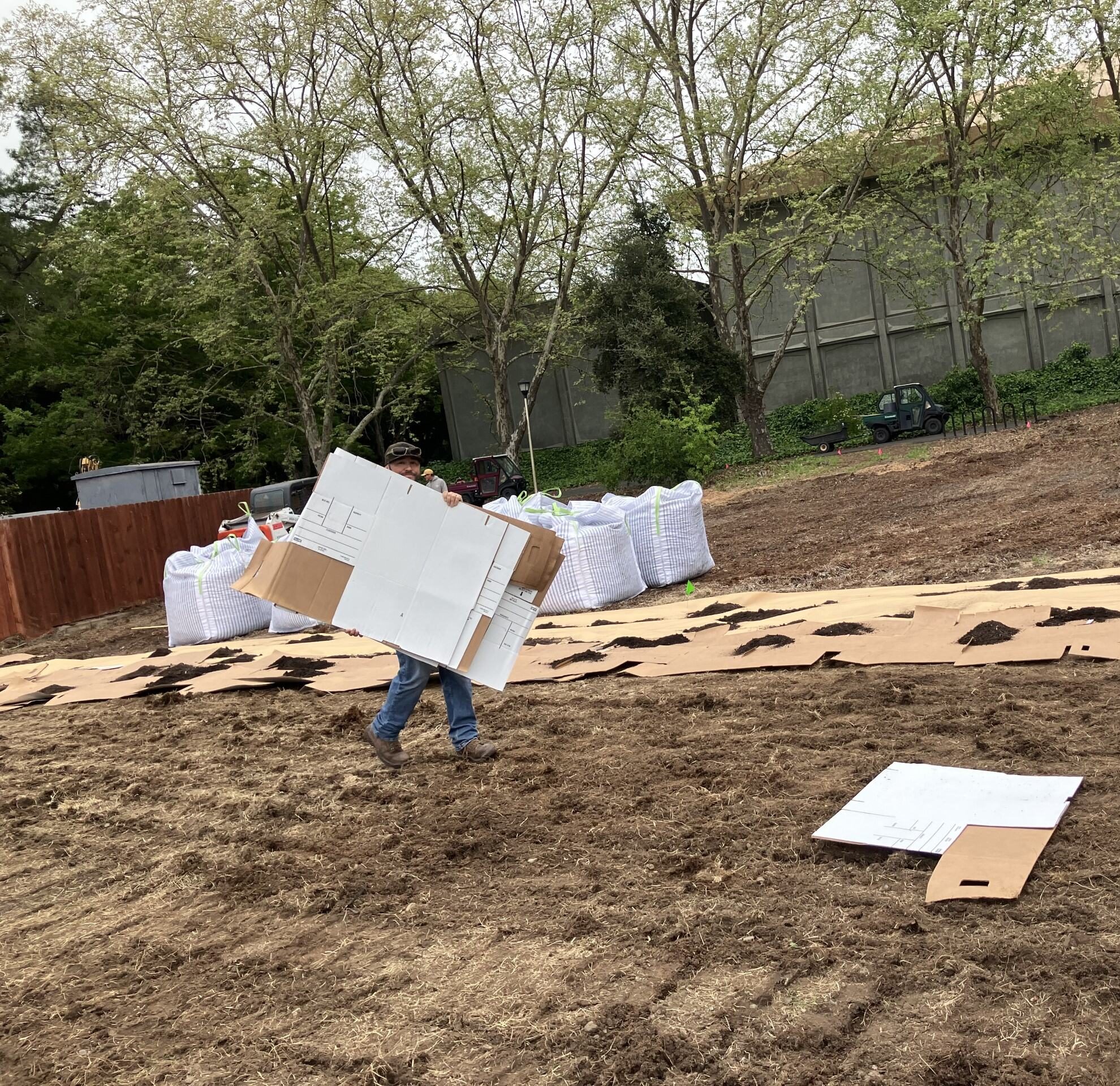 person carrying cardboard and cardboard on ground