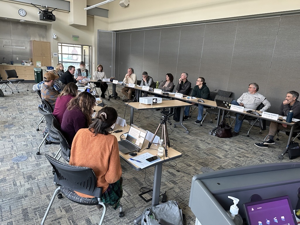a committee sits in a conference room around a large table