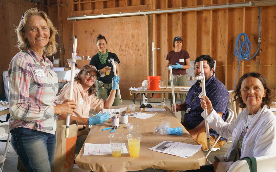 a group of people gather around a work table holding their DIY projects